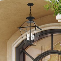 a lantern hanging from the side of a building with three lit candles in front of it