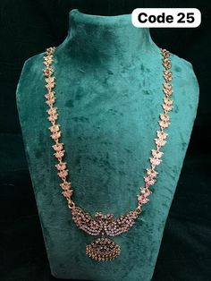 the necklace is on display in front of a green velvet mannequin with gold and pink stones