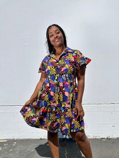 The Eloise is a sweet above-the-knee length dress. Made in our lightweight cotton poplin, this dress features a loose A-line silhouette with a collar, buttons all the way down the front, and has ruffled short sleeves and a tiered skirt that give it a fun whimsical vibe. 👩‍🎨 Featuring artwork by Neya Cotton Shirt Dress With Ruffles For A Day Out, Cotton Collared Shirt Dress With Ruffles, Collared Cotton Shirt Dress With Ruffles, Summer Cotton Shirt Dress With Ruffles, Summer Ruffled Collared Dress, Summer Collared Ruffle Dresses, Cotton Mini Shirt Dress With Ruffles, Summer Collared Dress With Ruffles, Collared Cotton Dresses With Ruffles