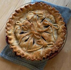 a pie sitting on top of a wooden table next to a blue napkin and fork