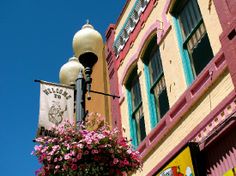 a street light with flowers hanging from it's side in front of a building