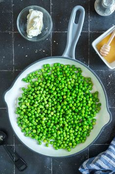 peas and cheese in a skillet on a counter with measuring spoons next to it