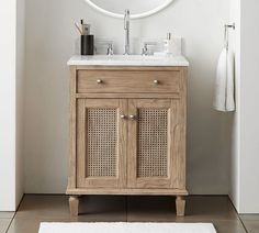 a bathroom vanity with a round mirror above it and a white rug on the floor