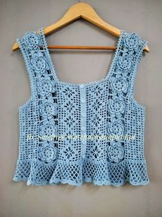 a blue crochet top hanging on a wooden hanger, with the back of it