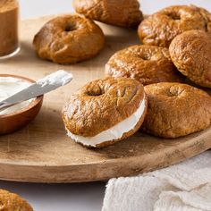 several baked goods on a wooden platter with a bowl of yogurt in the background