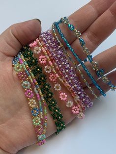 a person's hand holding several bracelets in different colors