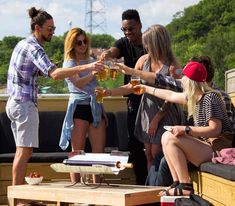 a group of friends toasting with beer on a picnic table in the back of a pick up truck