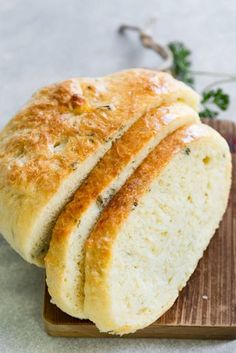 two loaves of bread sitting on top of a cutting board next to some parsley