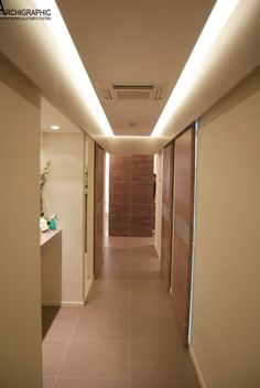 an empty hallway with lights on the ceiling and tile flooring in front of it