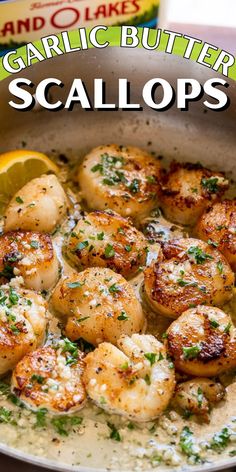 garlic butter scallops in a pan with lemon wedges