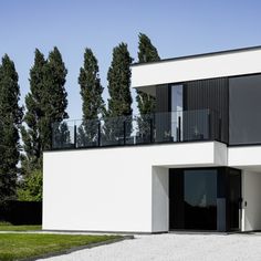 a white house with black balconies and trees in the background