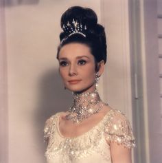 a woman in a white dress wearing a tiara and diamond necklace with pearls on her neck