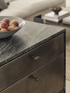 a bowl of peaches sitting on top of a marble topped dresser in a living room