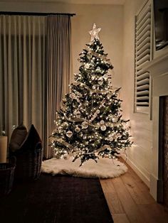 a small christmas tree in the corner of a room with lights on and a rug underneath it