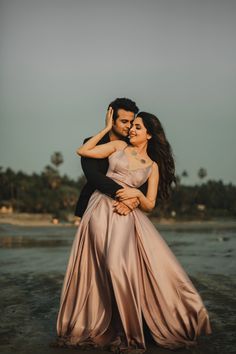 a man and woman hugging each other on the beach