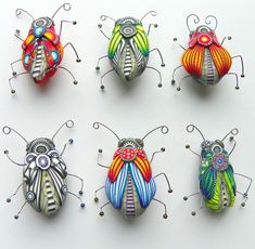 six colorful bug sculptures sitting on top of a white surface