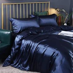 a bed with blue sheets and pillows in a room next to a green chair on the floor