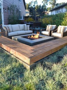 a fire pit sitting in the middle of a lush green field next to a house