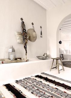 a room with white walls and rugs on the floor