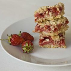 two pieces of strawberry bars on a plate with strawberries next to the same one