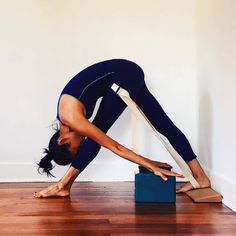 a woman is doing yoga on the floor with her hands behind her head and legs bent forward