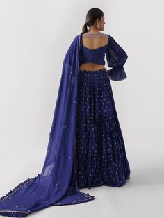 A three-piece Purple lehenga set from the Suruchi Parakh collection. This elegant georgette crepe lehenga is paired with a hand-embroidered blouse. The outfit is completed with a matching georgette crepe dupatta. The bell sleeve blouse has a cutwork neckline. And, the purple dupatta has a beautiful touch of ruffle with an embellished border. Georgette Palazzo Set With Cutdana For Reception, Traditional Drape Palazzo Set With Unstitched Blouse, Designer Wear Fitted Georgette Pre-draped Saree, Anarkali Style Floor-length Pre-draped Saree In Georgette, Georgette Palazzo Set With Cutdana For Navratri, Navratri Georgette Palazzo Set With Cutdana, Reception Anarkali Set With Dori Work In Georgette, Eid Georgette Choli With Cutdana, Reception Georgette Anarkali Set With Dori Work