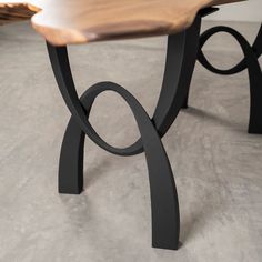 a wooden bench sitting on top of a cement floor next to a table with metal legs