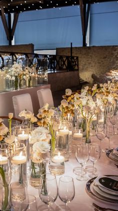 a long table is set with flowers and candles for a formal dinner or function in the evening