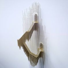 an artistic sculpture made out of strings and wood sticks in the shape of a spiral staircase