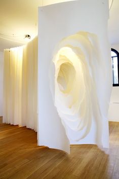 a room with white walls and wooden flooring that has an abstract sculpture in the center