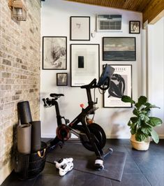 an indoor exercise bike in the corner of a room with pictures on the wall behind it