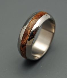 a silver ring with wood inlays on the outside and inside, sitting on a gray surface