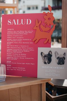 a pink sign with an image of a dog on it next to a small card that says salud