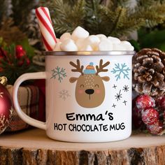 a christmas mug filled with hot chocolate and marshmallows on top of a wooden table