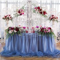 a table with flowers and candles on it in front of a curtained window at a wedding reception