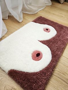 a brown and white rug on the floor with two pink eyeballs in it's center