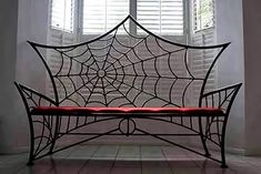 a spider web on the back of a bench in front of two windows with white shutters