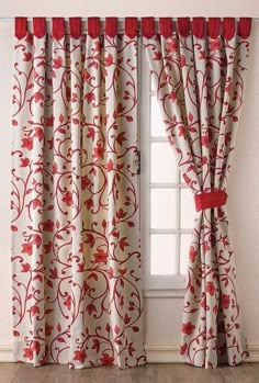 a red and white curtain hanging on the side of a window next to a wooden floor