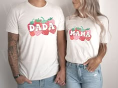 a man and woman wearing matching tshirts with strawberries on their shirts that read dada