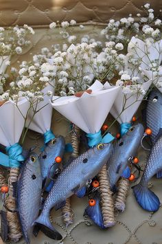 several fish are tied to small white cones with blue ribbons and flowers in the background