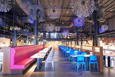 an empty restaurant with blue and pink chairs, tables and chandeliers hanging from the ceiling