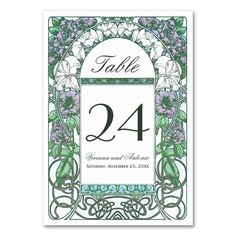 a wedding table number card with flowers and vines on the front, in green and white