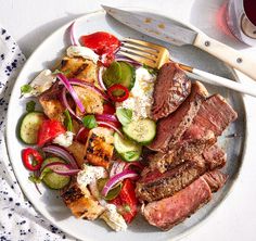 a white plate topped with meat and veggies next to a glass of wine