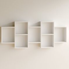 three empty white shelves are hanging on the wall