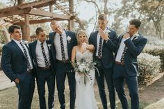 a group of people standing next to each other in front of some trees and bushes