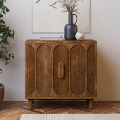 a wooden cabinet sitting on top of a hard wood floor next to a potted plant