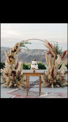 an outdoor wedding setup with pamodia and cake on the table, surrounded by greenery