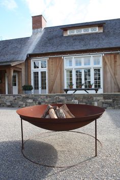 a fire pit in front of a house with windows and doors on the back wall