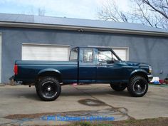 a blue pick up truck parked in front of a garage