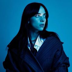 a woman with dark hair and blue eyes wearing a black jacket, white shirt and tie